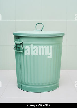 A metal trash can or waste bin green colored on white background Stock Photo