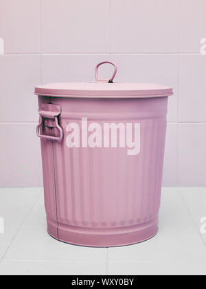 A metal trash can or waste bin pink colored on white background Stock Photo