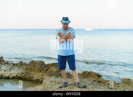 young man in hat and shorts posing on the seashore Stock Photo