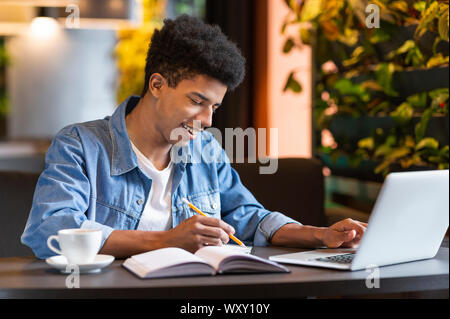 Successful african student working on project at cafeteria Stock Photo