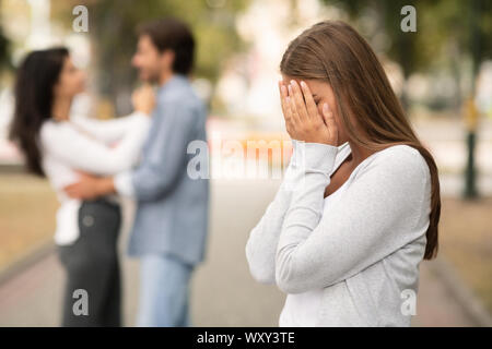 Upset woman crying, seeing her boyfriend with other girl Stock Photo