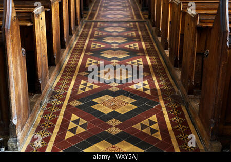 A detail view of the pews and aisle with victorian tiles at St. Cuthbert's Church in Wells, Somerset Stock Photo