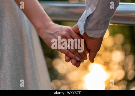 Close up of wedding rings on bride and groom hands. Giving of wedding rings outdoors at summer or autumn park Stock Photo