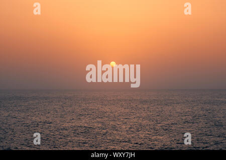 sunset on water, sun going down behind ocean - Stock Photo
