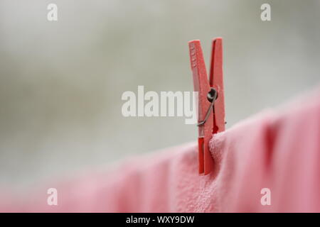 Red clothespin holds clothes on a rope, macro image. Stock Photo