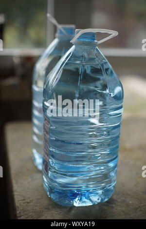 Two five-liter plastic bottles full of water on the table, side  Stock Photo