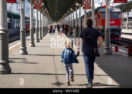 People walk on the platform of the Moscow Belorussky railway station with commuter trains and long-distance trains in Moscow, Russia Stock Photo