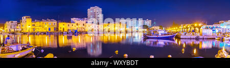 BIZERTE, TUNISIA - SEPTEMBER 4, 2015: Panorama of evening port, with many moored boats and illuminated buildings, reflected on water surface, on Septe Stock Photo