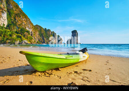 Enjoy Andaman seascape with a small green boat on the sand Monkey Beach and Ao Nang Tower rock on the background, Krabi, Thailand Stock Photo