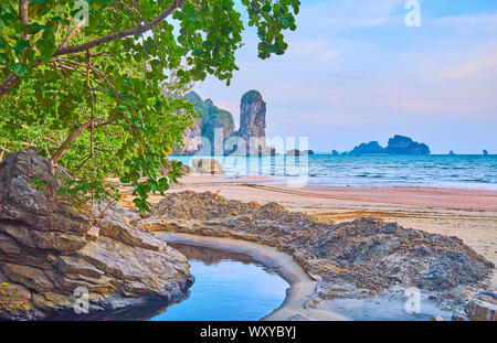 The stunning landscape from the Tonsai Bay coast with a view on narrow winding creek, tropical greenery, sand beach and tall rock of Ao Nang Tower, Kr Stock Photo