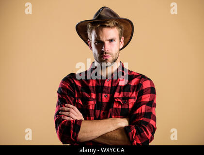 American cowboy. Beauty standard. Example of true masculinity. Cowboy wearing hat. Western life. Man unshaven cowboy beige background. Unshaven guy in cowboy hat. Handsome bearded macho. Stock Photo