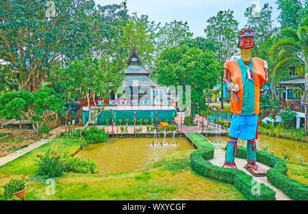 PAI, THAILAND - MAY 5, 2019: The metal statue of Karen tribe long neck woman in colorful clothes, standing among the small ponds in park of the countr Stock Photo