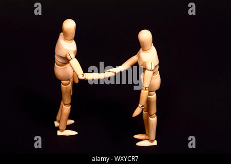 Conceptual image of wooden manikins shaking hands Stock Photo
