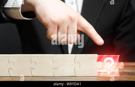 Businessman finger points to the absence of a component in the puzzle chain. Missing or missing component or element. Not enough to complete the proje Stock Photo