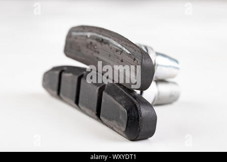 Worn and new brake pads for the bicycle. Replacement and service of bicycle parts in the workshop. Light background. Stock Photo