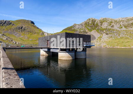 The valve building inLlyn Stwlan, the upper reservoir of the Ffestiniog power station. Moelwyn Bach stands at the far end of the dam Stock Photo
