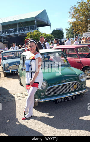 September 2019 -  Models in classic 1960's style dress's at the Goodwood Revival meeting leaning on a Classic Austin Mini Cooper S Stock Photo