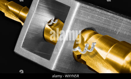 Titanium coated step drill bit. Artistic detail on black background. Drilling holes by steel unibit. Metal shavings. Aluminium profile. Chip machining. Stock Photo