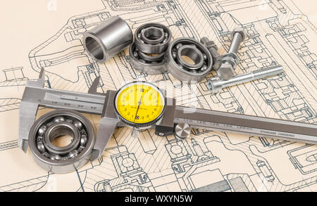 Analog caliper detail. Accurate measuring of a ball bearing diameter on technical drawing background. Vernier gauge with round yellow dial. Metal tool. Stock Photo