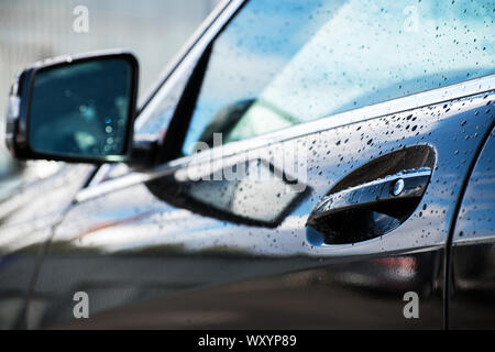 car door handle and part of a car with a rearview mirror at shallow depth of field Stock Photo