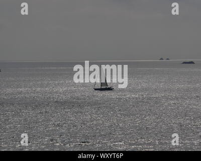 Photo de l'océan a contre jour , avec un voilier , océan couleur argent a contre jour , îlots perdus en mer Stock Photo