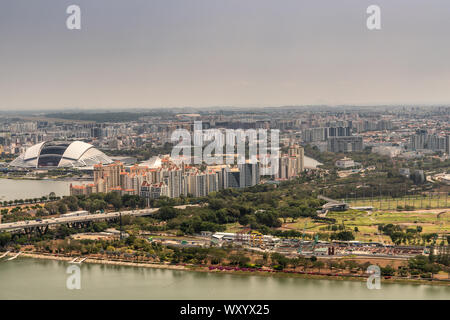 Singapore - March 21, 2019: Shot from Sands roof. Birds eye view on open National Stadium with housing and hundreds of skyscrapers in wide area. Silve Stock Photo