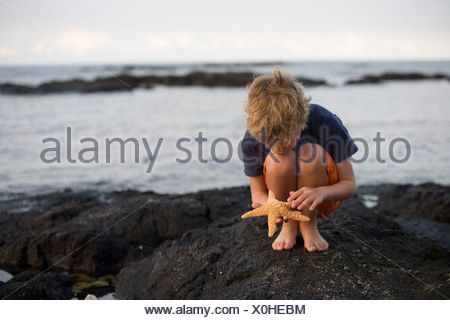 Boy crouched down outside Stock Photo - Alamy