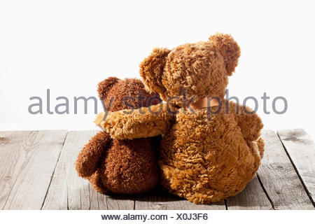 Back view of two teddy bears with their arms around each other, sitting ...