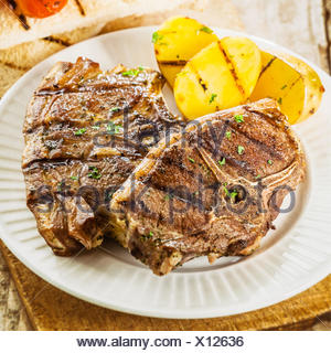 Two grilled lamb chops served with french fried potato chips and a