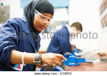 Female student using vice grip in college workshop