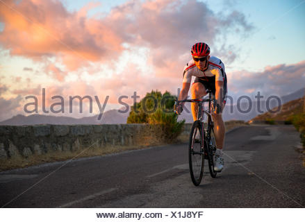 Man cycling at sunset, Corsica, France