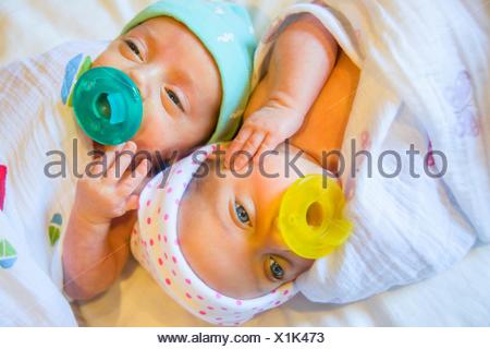 Twin baby sister and brother sucking on comforter Stock Photo: 85719356