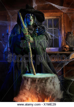 Scary old witch stirring potion in a cauldron inside her cabin on Stock ...