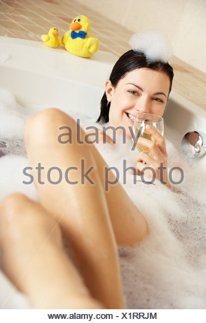 Woman Relaxing With Glass Of Wine In Bubble Filled Bath