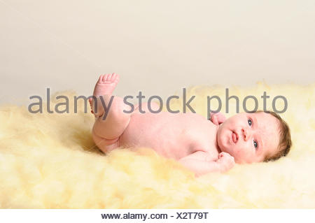 Ein kleines neugeborenes Baby liegt auf einem Schaffell.