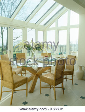 High-back wicker chairs and glass table in modern conservatory ... High-back wicker chairs and glass table in modern conservatory ...