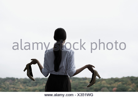 A businesswoman holding high heeled shoes