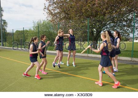 Group of girls on sports field with rounders bats