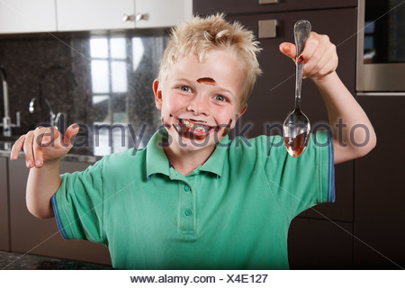 Boy in kitchen with cake mix on his face