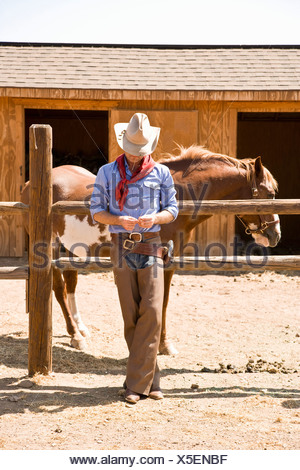 A cowboy leaning against a fence on a ranch