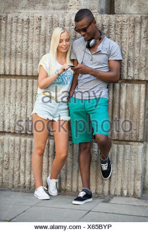 lachende junge freunde im sommer in der stadt mit mobiltelefon