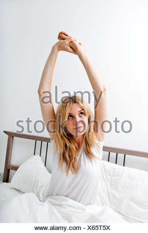 Young woman stretching in bed