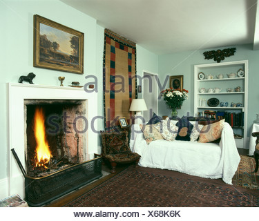 Country Livingroom With Fire Lit In Fireplace And Sofa With White