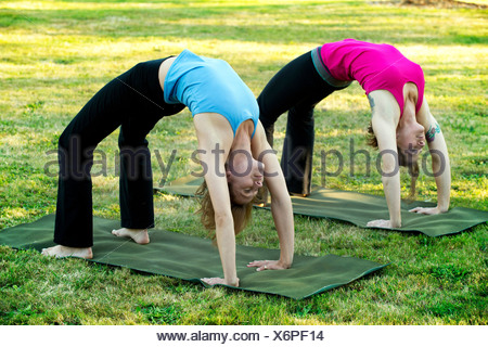 Two mature women bending over sideways whilst exercising in living ...