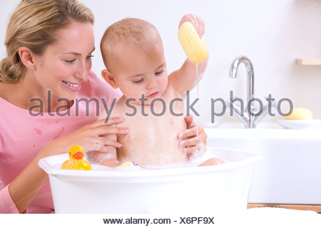 Woman giving bath to her baby in a wash bowl Stock Photo: 57526134 - Alamy