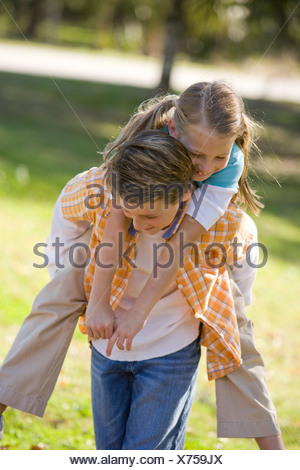 Boy giving piggyback ride to girl in park