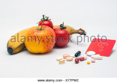 verschiedene bunte Tabletten, Apfel, Banane, Tomaten und rotes Fragezeichen-Schild, isoliert