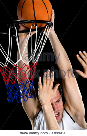 A basketball player trying to make a basket, studio shot