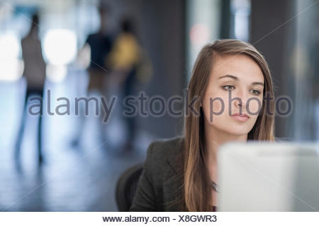 Young businesswoman sitting at desk, using computer