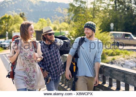 Three people walking together carrying backpacks, smiling